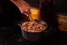 a person cooking food in a pot on the grill