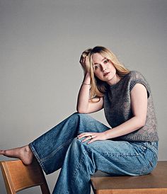 a woman sitting on top of a wooden table with her legs crossed and looking at the camera