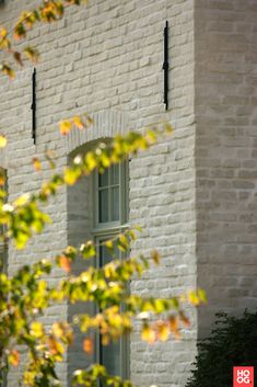 a white brick building with two windows and a clock on the side of it's face