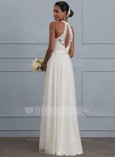 a woman in a white wedding dress looking at the back of her gown, holding a bouquet