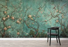 a chair sitting in front of a wall with flowers and branches painted on the wall