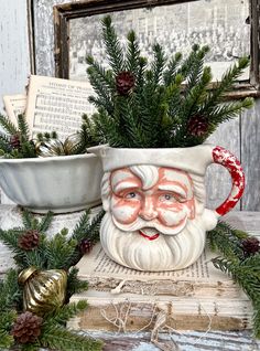 an old fashioned christmas mug with a santa face on it and pine cones around the rim