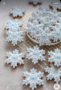 some cookies are on a cooling rack and have been decorated with blue icing or snowflakes