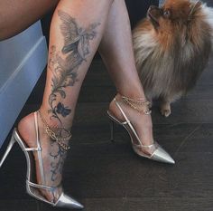 a woman's legs with tattoos on them and a small dog sitting next to her