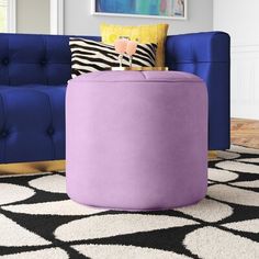 a living room with a blue couch and purple ottoman on top of a black and white rug