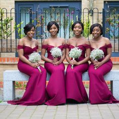 three beautiful women in long dresses sitting on a bench with white flowers and greenery