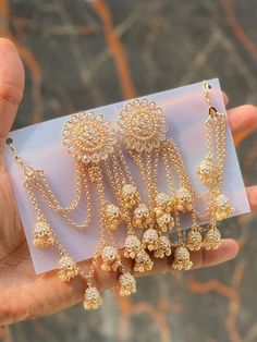 three pairs of gold - plated earrings are being held by a hand