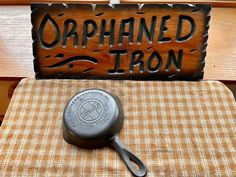 a cast iron skillet sitting on top of a table next to a wooden sign