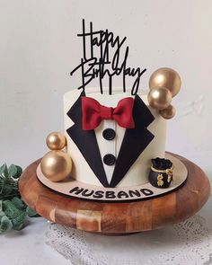 a birthday cake decorated with an image of a tuxedo and two gold balls