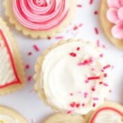 several decorated cookies on a table with sprinkles and pink flowers in the background