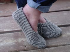 someone is wearing slippers made out of knitted wool, and they are standing on a wooden platform