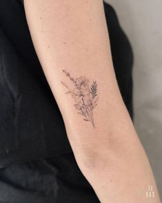 a woman's arm with a small flower tattoo on the left side of her arm