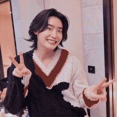 a person standing in front of a mirror making the v sign with their hands and smiling