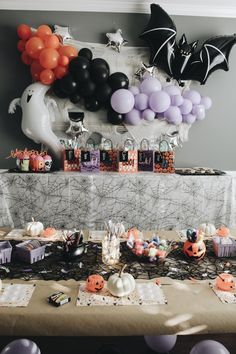 a table topped with lots of halloween decorations and balloons on it's head,