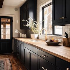 a kitchen with black cabinets and wooden counter tops