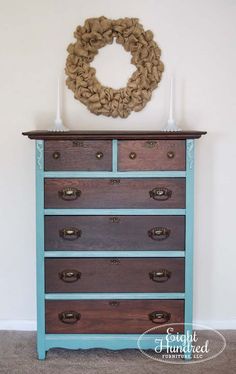 an old dresser has been painted blue and brown with a wreath on top of it