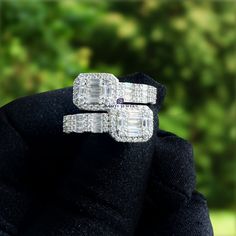 two diamond rings sitting on top of each other in front of some trees and bushes