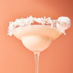 a drink in a martini glass with coconut garnish on top