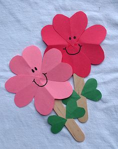 three paper flowers with faces drawn on them