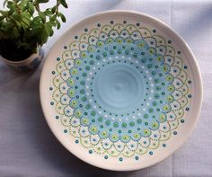 a blue and green bowl sitting next to a potted plant