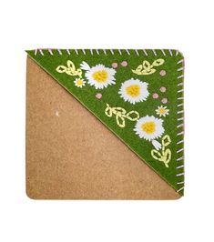 a green and yellow triangle with daisies on the side, sitting on top of a piece of cardboard