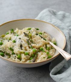 a bowl filled with rice, peas and parmesan cheese on top of a table