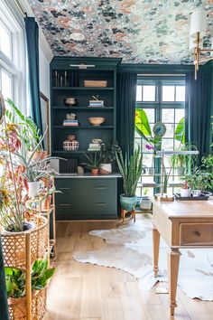 a living room filled with lots of plants and potted plants on top of a wooden table