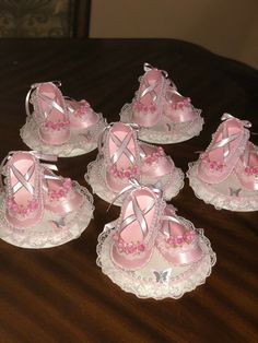 six pink baby shoes are sitting on lace doily, with bows and ribbons around them