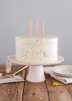 a white cake with sprinkles and candles sitting on top of a table