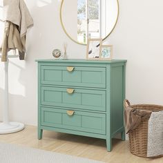 a green dresser sitting in front of a mirror on top of a wooden floor next to a wicker basket