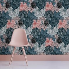 a pink chair sitting in front of a wall with blue and pink flowers on it