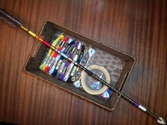 an assortment of crafting supplies in a tray on top of a wooden table with scissors