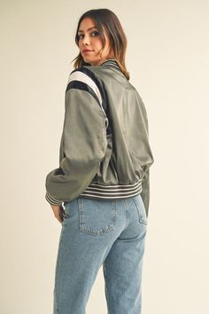 This Green Gray Cropped Satin Bomber Varsity Jacket is the ideal combination of style and warmth, perfect for any casual or formal occasion. Crafted with a luxuriously soft satin fabric and comfortable long sleeves, this jacket features attractive contrast color detailing that adds to its sophistication. The soft interior lining ensures maximum wearability and comfort. Fabric & fit: SELF: 92% POLYESTER 8% SPANDEXLINING : 100% POLYESTERCONTRAST: 96%POLYESTER 4%SPANDEX Model is wearing size Small. Long Sleeve Varsity Jacket With Contrast Color For Fall, Fall Contrast Color Long Sleeve Varsity Jacket, Trendy Spring Varsity Jacket With Contrast Color, Trendy Varsity Jacket With Contrast Color For Spring, Casual Long Sleeve Track Jacket With Contrast Trim, Spring Satin Outerwear With Long Sleeves, Winter Satin Long Sleeve Outerwear, Spring Satin Long Sleeve Outerwear, Long Sleeve Varsity Jacket For Workwear