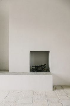 a fire place in the middle of a room with white walls and tile flooring