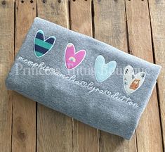 a gray towel with hearts on it sitting on top of a wooden floor