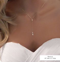 the back of a woman's neck wearing a necklace with a diamond drop on it