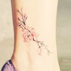 a woman's foot with a flower tattoo on the side of her leg and ankle