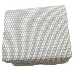 a white and grey blanket on top of a bed with the cover pulled down to reveal an interesting pattern