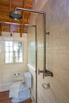 a bathroom with a shower, toilet and window on the wall in front of it