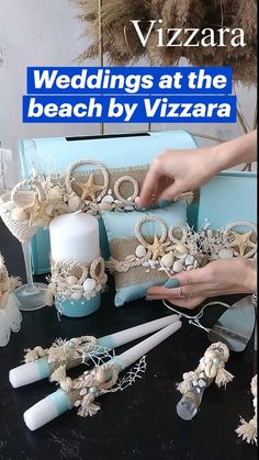 a table topped with blue boxes covered in shells and seashells next to candles