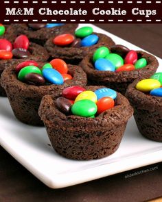 chocolate cupcakes with m & m candy in the middle on a white plate