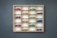 a wooden shelf filled with toy cars on top of a gray wall next to a blue wall