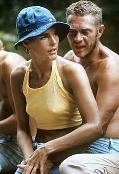 a man and woman sitting next to each other on the ground with trees in the background