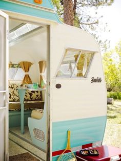 an old camper converted into a tiny house with the door open and windows opened