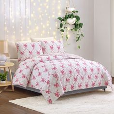 a bed with pink and white bedspread on top of it next to a potted plant