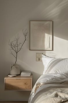 a bed with white sheets and pillows next to a painting on the wall above it