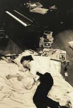 a man laying on top of a bed next to a piano