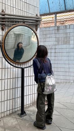 a woman standing in front of a round mirror