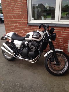 a white and black motorcycle parked in front of a red brick building next to a window