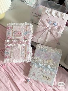 three boxes are sitting on a table with pink sheets and lace trimmings around them